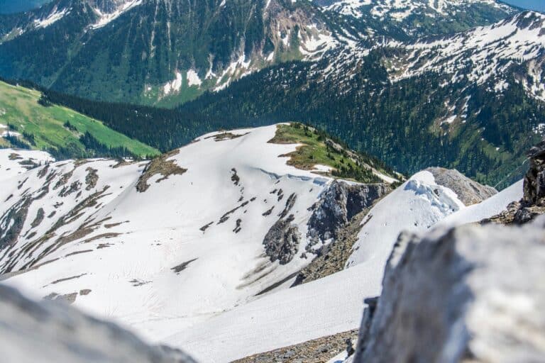 Frühsommer in den kanadischen Rocky Mountains mit Blick auf teilweise freie und grüne, teilweise noch schneebedeckte Bergkuppen