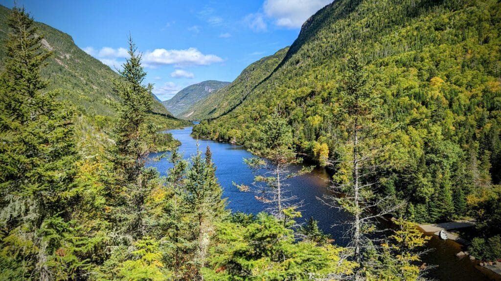 Blick auf den blauen Fluss zwischen grünen Berghängen im Parc national des Hautes‑Gorges-de-la-Rivière‑Malbaie