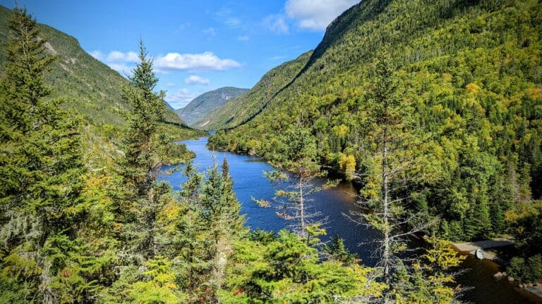 Blick auf den blauen Fluss zwischen grünen Berghängen im Parc national des Hautes‑Gorges-de-la-Rivière‑Malbaie