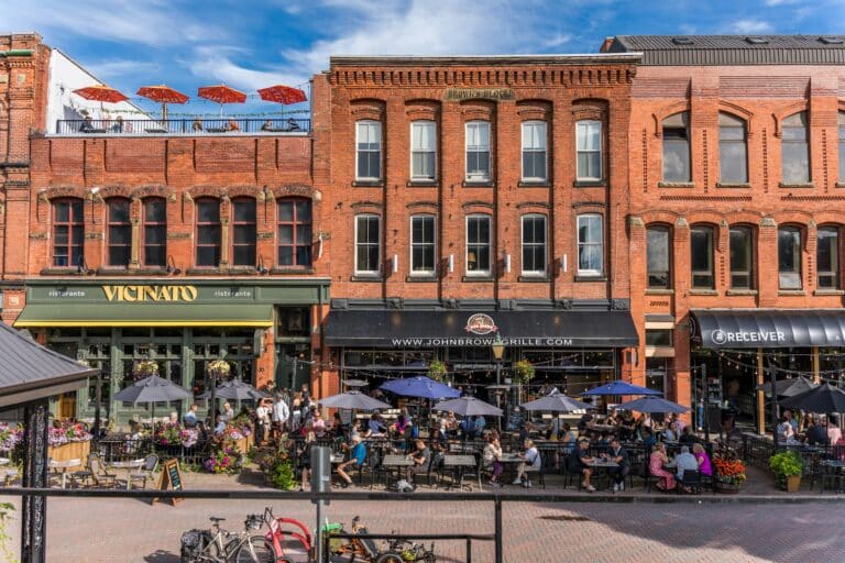 Backsteinhausreihe im sommerlichen Charlottetown mit gut besuchten Restaurants, wo viele Gäste an Tischen im Fußgängerbereich sitzen